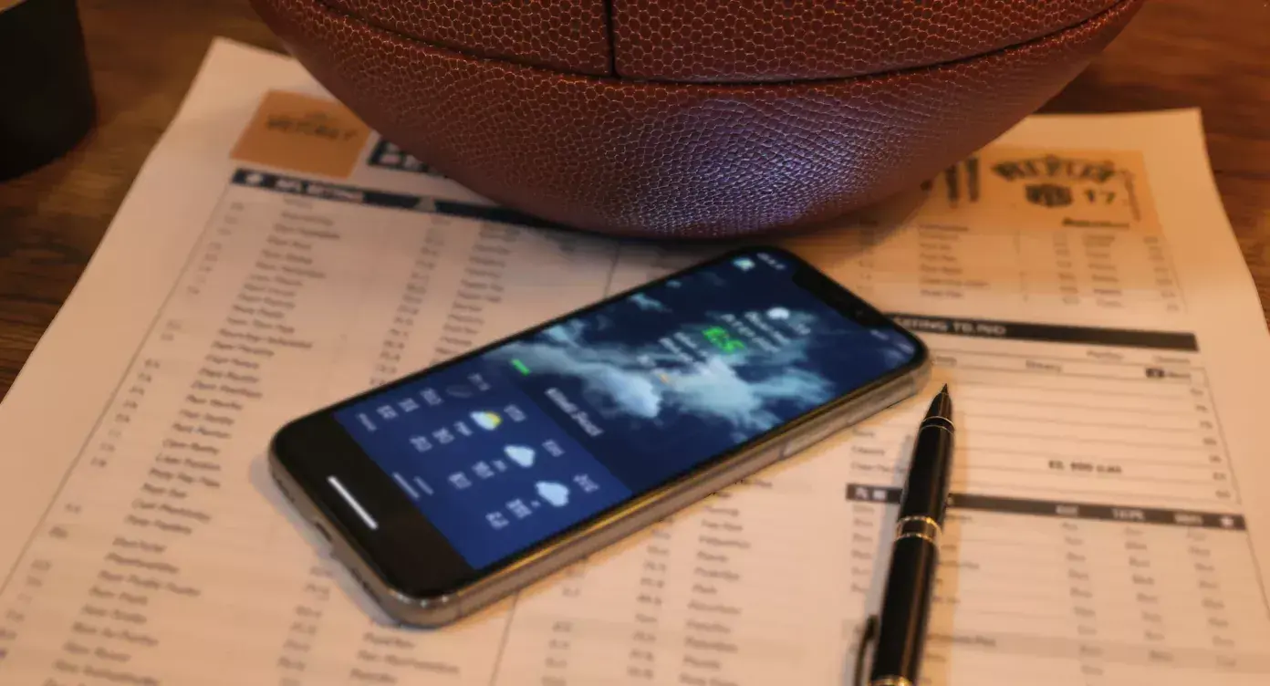 UK punter reading NFL injury report on screen with weekly betting sheet
